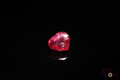 a close up of a red heart shaped diamond on a black surface