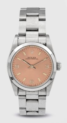 un gros plan d'une montre posée sur une surface blanche, avec un cadran rose