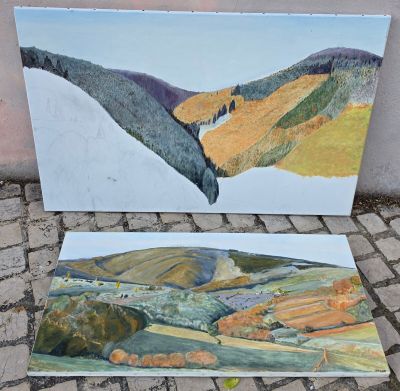deux tableaux représentant un paysage, posés sur un sol en briques près d'un mur