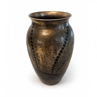 un vase marron percé de trous posé sur une surface blanche