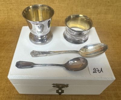 une tasse et une cuillère en argent posées sur une boîte blanche