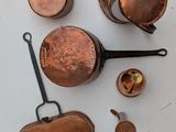 a lot of copper pots and pans on the table