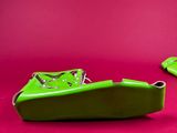 pair of green shoes on a pink surface with a red background