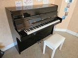 a piano in the corner of a room with a stool
