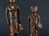 two wooden statues of a man and a woman standing next to each other