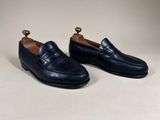 a pair of black leather loafers with a gold toe