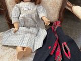 a doll that is sitting on a chair next to a coat