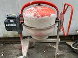 a cement mixer sitting on the ground next to a wall