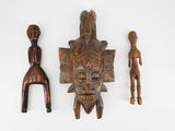 un ensemble de trois masques en bois sculpté sur un fond blanc