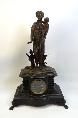 une statue représentant une femme tenant un enfant dans ses bras, au sommet d'une horloge
