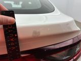 a person holding a ruler in front of a white car
