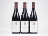 trois bouteilles de vin rouge posées l'une à côté de l'autre sur une surface blanche