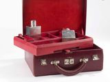 une valise rouge contenant un flacon de parfum