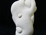 a white stone sculpture on a stand against a black background
