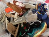 many pairs of shoes in a basket on a bed
