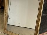 une image représentant un miroir à cadre doré posé à même le sol