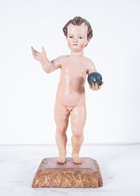 une figurine représentant un garçon tenant un ballon, posée sur un socle en bois