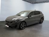 La voiture grise est garée dans une grande pièce aux murs blancs.