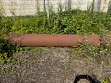a rusted pipe laying on the ground next to a fence