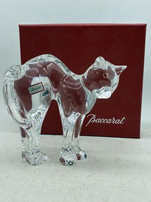 une figurine de chat en verre posée à côté d'une boîte rouge
