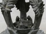 a statue of a frog sitting in a basket with leaves on it