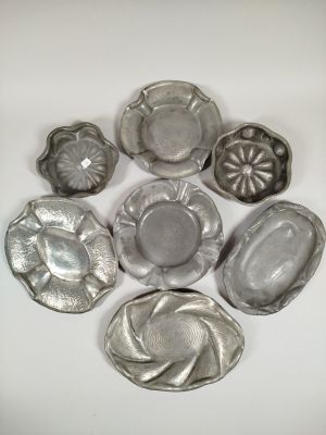 several silver metal dishes are arranged in a circle on a white surface