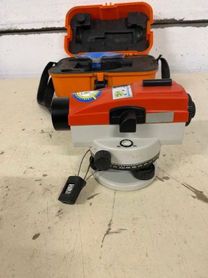 an orange and white surveying device sitting on top of a white floor