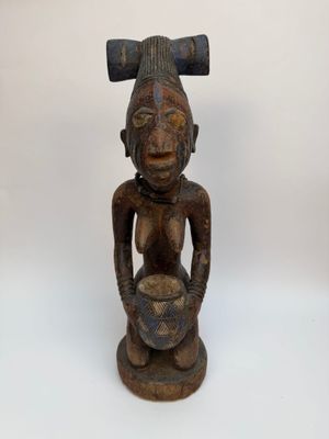 une vieille statue en bois représentant un homme tenant un bol