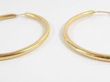 a pair of gold hoop earrings on a white surface