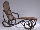 un vieux fauteuil à bascule avec une assise et un repose-pieds en bois, posé sur une surface blanche