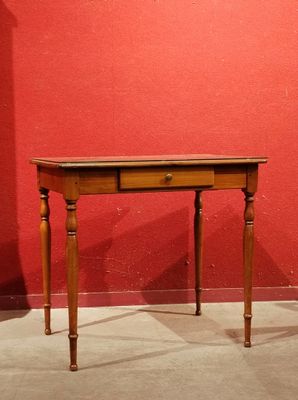 a small table with a drawer on it in front of a red wall