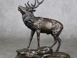 statue d'un cerf debout sur un rocher, avec des bois dans ses bois