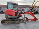 a small red excavator that is parked in a parking lot