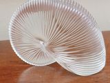 a glass object on a wooden table with a white wall in the background