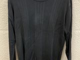 a black sweater hanging on a hanger against a wall