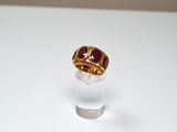 une bague en or sertie d'une pierre rouge sur un verre transparent