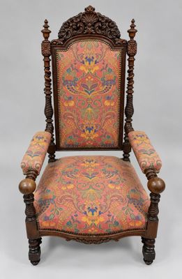 an old chair with a colorful upholstered back and arms