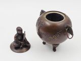 a small statue of a man sitting next to a vase