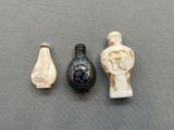 trois objets sculptés sont posés sur une surface grise