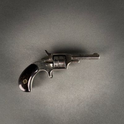a close up of a gun on a table with a gray background