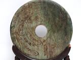 a carved green stone disc on a stand with a mirror