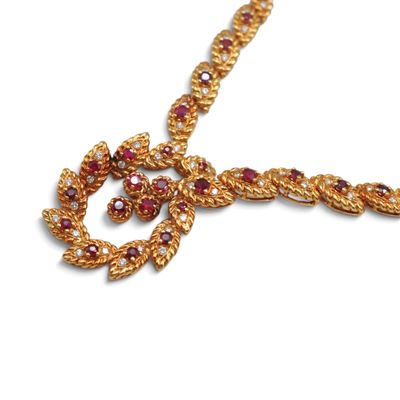 une image représentant un collier en or orné de pierres rouges et blanches, sur fond blanc