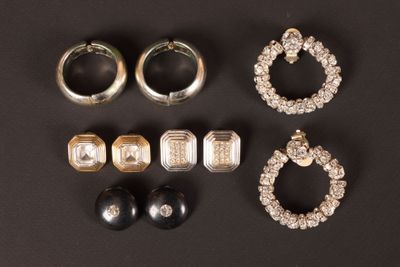 trois paires de boucles d'oreilles et une bague posées sur un fond noir