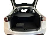 the back of a white car with its trunk open and a laptop in the trunk