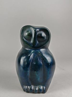 figurine de chouette en céramique bleue posée sur une surface blanche