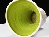 a green cup sitting on top of a white table