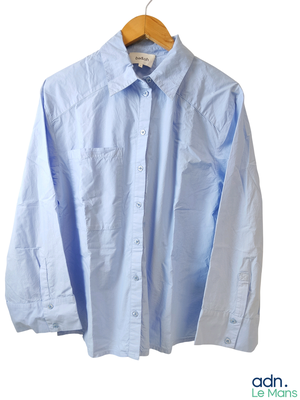 une chemise bleue suspendue à un cintre sur un mur blanc
