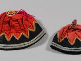 une paire de petits chapeaux rouges et noirs ornés d'un motif rouge et jaune