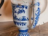 a blue and white vase with a handle on a table