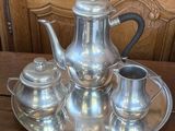 a silver tea set on a silver tray on a wooden table